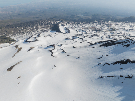 Aerial view of the snow covered volcanic craters and dark lava flows on the south slope of Mount Etna in Nicolosi Sicilia Italy. Aerial view of the snow covered volcanic craters and dark lava flows on the south slope of Mount Etna in Nicolosi Sicilia Italy.