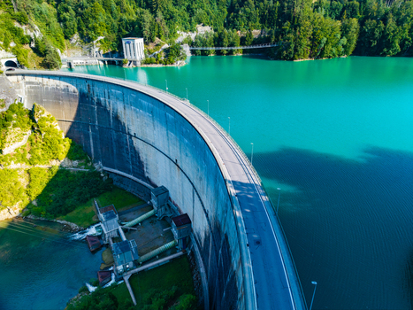 Aerial view of the Barrage de Rossens dam arching over the turquoise waters of Lac de la Gruyere surrounded by dense green forests in Pont la Ville Fribourg Switzerland.