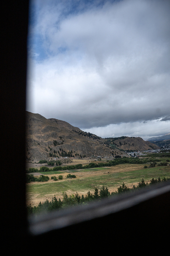 View of the landscape seen from the window of The Trochita Old Patagonian Express with rolling hills green fields and a cloudy sky in Esquel Chubut Argentina.