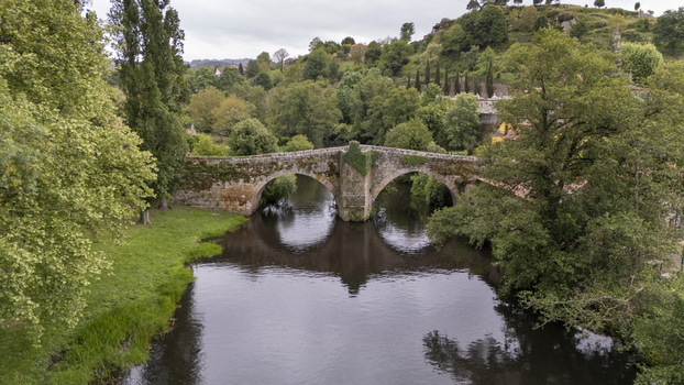 Aerial view of Ponte de Vilanova crossing the Arnoia River surrounded by lush green trees and vegetation in Allariz Ourense Spain. Aerial view of Ponte de Vilanova crossing the Arnoia River surrounded by lush green trees and vegetation in Allariz Ourense Spain.