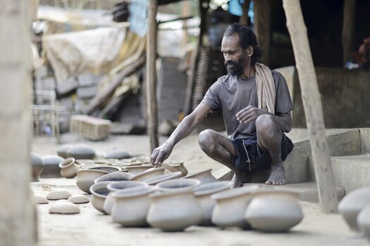 Odisha India 26 March 2026 View of a craftsman in Odisha carefully arranging freshly made earthen pots their raw clay texture contrasting with the weathered surroundings. Odisha India 26 March 2026 View of a craftsman in Odisha carefully arranging freshly made earthen pots their raw clay texture contrasting with the weathered surroundings.