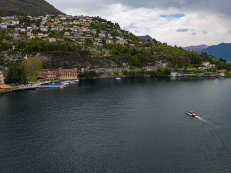 Aerial view of Villa d Este on the shores of Lake Como with historic architecture a lush green hillside and a boat cruising on the water in Cernobbio Lombardia Italy. Aerial view of Villa d Este on the shores of Lake Como with historic architecture a lush green hillside and a boat cruising on the water in Cernobbio Lombardia Italy.