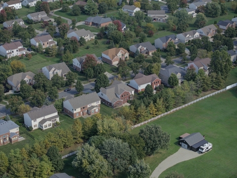 Aerial view of a suburban neighborhood with detached houses green lawns mature trees and winding streets in Mason Ohio United States.