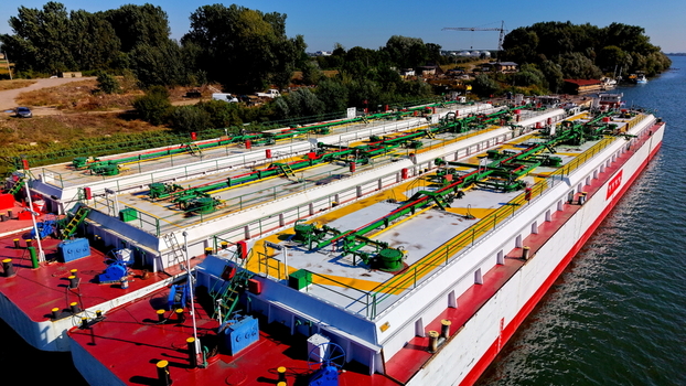 Aerial view of industrial barges docked on the Danube River near the Smederevo shipyard featuring red and white hulls and green piping in Smederevo Podunavlje District Serbia.