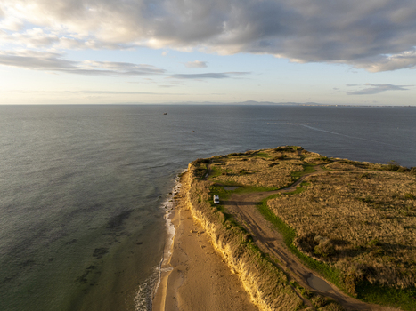 Aerial view of coastal cliffs and sandy beach with a dirt path and parked vehicle under a soft sky in Nessebar Burgas Bulgaria. Aerial view of coastal cliffs and sandy beach with a dirt path and parked vehicle under a soft sky in Nessebar Burgas Bulgaria.