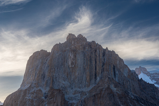 View of the dramatic jagged rock spires of the Baltoro Glacier region featuring sheer vertical cliffs and craggy peaks under wispy clouds Baltoro Gilgit Baltistan Pakistan.
