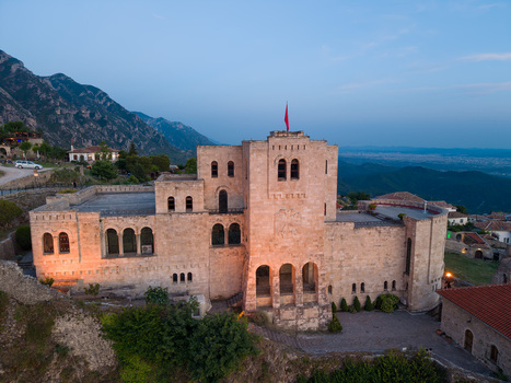 Aerial view of the historic Kruje Castle with its stone walls and towers under a soft dusk light against a backdrop of rugged mountains in Kruje Durres County Albania.