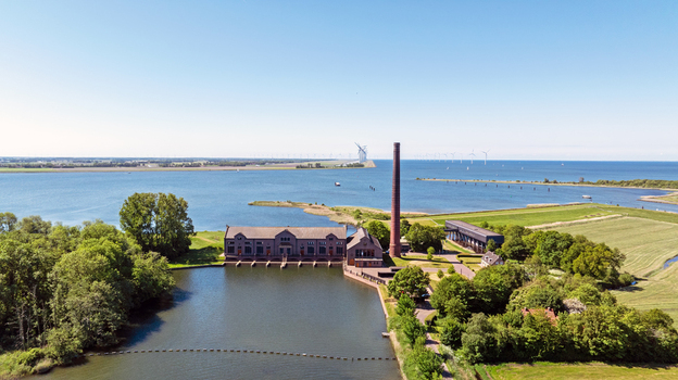 Aerial view of Wouda pumping station a historic UNESCO site with its iconic brick chimney and industrial buildings along the water in the Dutch landscape. Lemmer Friesland Netherlands.