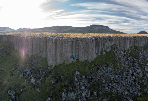Aerial view of the basalt columns of Gerduberg Cliffs with a person standing at the base rocky terrain and green moss Raudhamelur Eyja og Miklaholtshr Iceland. Aerial view of the basalt columns of Gerduberg Cliffs with a person standing at the base rocky terrain and green moss Raudhamelur Eyja og Miklaholtshr Iceland.