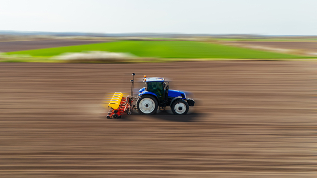 Aerial view of a tractor speeding across the vast freshly tilled field contrasting with vibrant green patches in the distance Sremska Mitrovica Vojvodina Serbia. Aerial view of a tractor speeding across the vast freshly tilled field contrasting with vibrant green patches in the distance Sremska Mitrovica Vojvodina Serbia.
