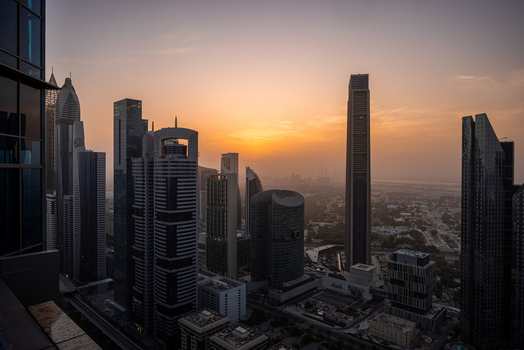 View of modern skyscrapers and high rise buildings under a golden sunset sky in the urban skyline of Dubai Dubai United Arab Emirates. View of modern skyscrapers and high rise buildings under a golden sunset sky in the urban skyline of Dubai Dubai United Arab Emirates.