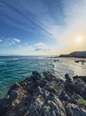 View of the rugged rocky coastline and turquoise ocean waves under a bright sun in Plettenberg Bay Western Cape South Africa. View of the rugged rocky coastline and turquoise ocean waves under a bright sun in Plettenberg Bay Western Cape South Africa.
