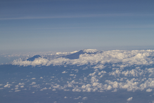 View of the snow capped peak of Mount Kilimanjaro rising above a dense layer of white clouds under a clear blue sky Tiwi Kwale Kenya. View of the snow capped peak of Mount Kilimanjaro rising above a dense layer of white clouds under a clear blue sky Tiwi Kwale Kenya.