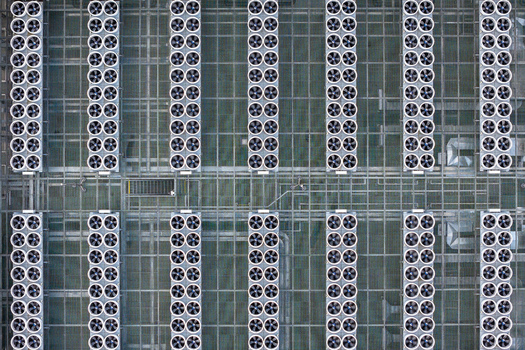 Aerial view of rows of industrial cooling fans on the rooftop of an AI data center with metal grating and compute grid infrastructure in Warsaw Masovian Voivodeship Poland. Aerial view of rows of industrial cooling fans on the rooftop of an AI data center with metal grating and compute grid infrastructure in Warsaw Masovian Voivodeship Poland.