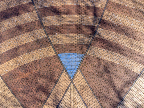 Aerial view of a patterned brick ground with contrasting brown and tan hues converging towards a central blue triangular accent Maastrichtkwartier Flevoland Netherlands. Aerial view of a patterned brick ground with contrasting brown and tan hues converging towards a central blue triangular accent Maastrichtkwartier Flevoland Netherlands.