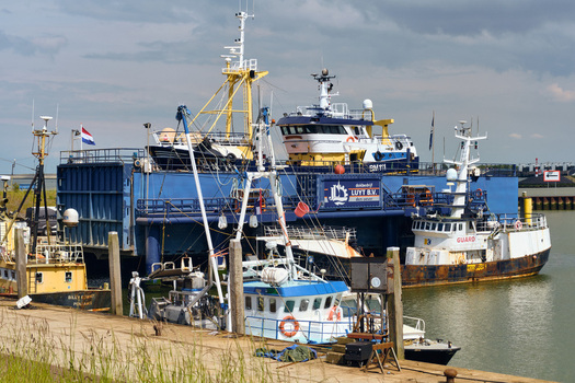 Den Oever Netherlands 18 May 2026 View of British fleet vessels being renovated at the Luyt B.V. shipyard with masts and industrial equipment under a cloudy sky.