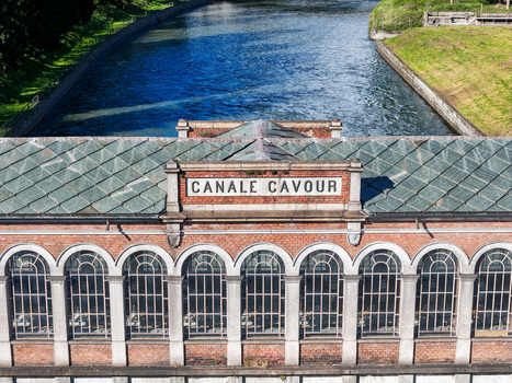 Aerial view of the historic Canale Cavour building featuring arched windows and the adjacent flowing canal in Chivasso Piedmont Italy.
