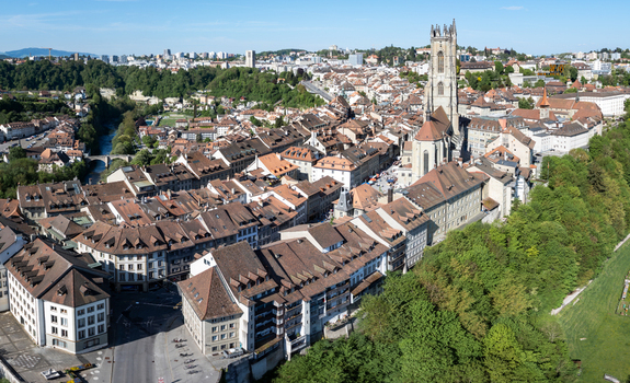 Aerial view of St Nicolas Cathedral and the historic old town rooftops with the Sarine river valley in Fribourg Fribourg Switzerland. Aerial view of St Nicolas Cathedral and the historic old town rooftops with the Sarine river valley in Fribourg Fribourg Switzerland.