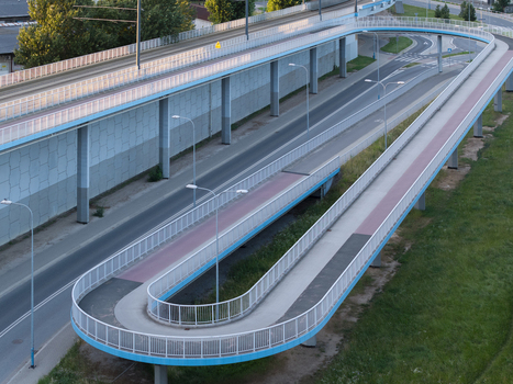 Aerial view of a modern U shaped pedestrian and bicycle overpass ramp with metal railings concrete supports and asphalt paths situated above a highway in Poland. Aerial view of a modern U shaped pedestrian and bicycle overpass ramp with metal railings concrete supports and asphalt paths situated above a highway in Poland.