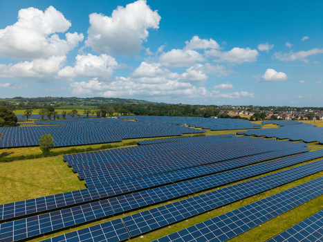 Aerial view of Lisburn Solar Farm with rows of photovoltaic panels set in green fields under a bright blue sky with white clouds in Lisburn Northern Ireland United Kingdom. Aerial view of Lisburn Solar Farm with rows of photovoltaic panels set in green fields under a bright blue sky with white clouds in Lisburn Northern Ireland United Kingdom.