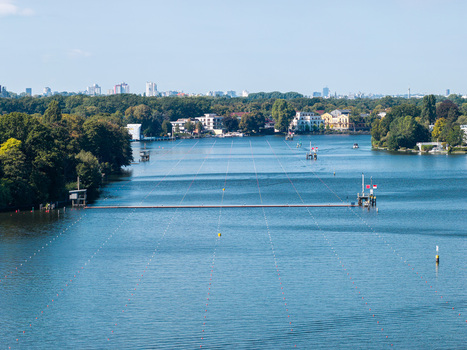 Aerial view of Berlin Grunau Regatta Course on the Dahme river with lane markers surrounding trees and distant city skyline in Berlin Berlin Germany. Aerial view of Berlin Grunau Regatta Course on the Dahme river with lane markers surrounding trees and distant city skyline in Berlin Berlin Germany.