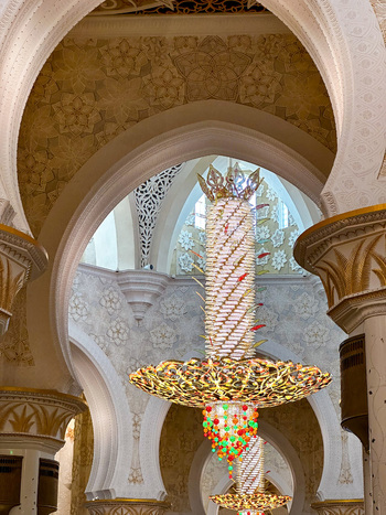 Abu Dhabi United Arab Emirates 15 October 2023 View of an intricate golden chandelier hanging under ornate white marble arches inside the Sheikh Zayed Grand Mosque.