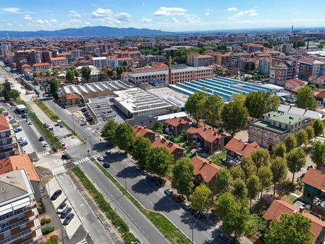 Aerial view of Villaggio Leumann featuring historic industrial buildings red roofed houses and lush green trees along the streets in Collegno Piemonte Italy. Aerial view of Villaggio Leumann featuring historic industrial buildings red roofed houses and lush green trees along the streets in Collegno Piemonte Italy.