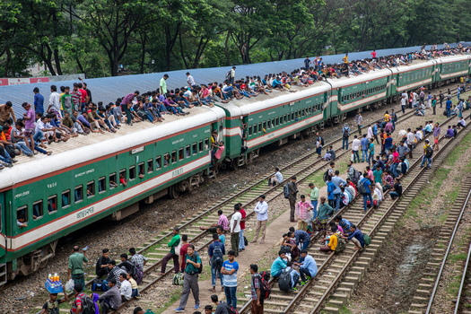 Dhaka Bangladesh 14 June 2018 View of the crowded Airport Railway Station with many people sitting on the roof of a green train and standing along the tracks. Dhaka Bangladesh 14 June 2018 View of the crowded Airport Railway Station with many people sitting on the roof of a green train and standing along the tracks.