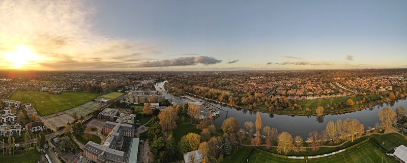 Aerial view of the River Thames winding through residential neighborhoods and green parks near the weir during sunset in Teddington England United Kingdom.