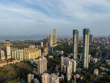 Aerial view of the modern skyline of Mumbai featuring tall skyscrapers dense urban residential complexes and lush green patches near the coastline in Mumbai Maharashtra India. Aerial view of the modern skyline of Mumbai featuring tall skyscrapers dense urban residential complexes and lush green patches near the coastline in Mumbai Maharashtra India.