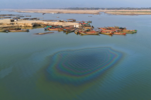 Aerial view of Jadukata River with numerous wooden boats moored along the sandy bank and a colorful oil slick on the water surface in Sunamganj Sylhet Division Bangladesh. Aerial view of Jadukata River with numerous wooden boats moored along the sandy bank and a colorful oil slick on the water surface in Sunamganj Sylhet Division Bangladesh.