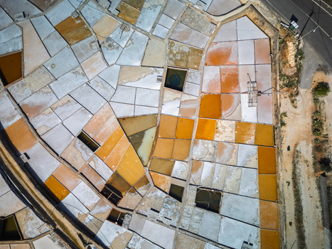 Aerial view of salt pans with geometric shapes and varying water colors in the salt production fields of Portugal. Aerial view of salt pans with geometric shapes and varying water colors in the salt production fields of Portugal.