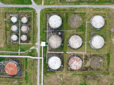 Aerial view of industrial oil storage tanks with interconnected pipelines and circular metal structures situated on grassy terrain in Olaine parish Olaine Municipality Latvia.