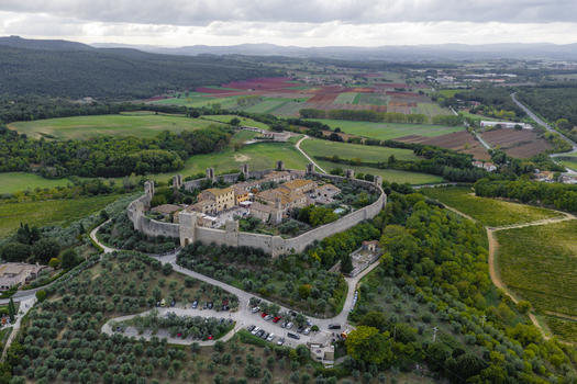 Aerial view of the medieval fortified town of Monteriggioni with its historic stone walls and towers surrounded by olive groves and vineyards in Monteriggioni Tuscany Italy.
