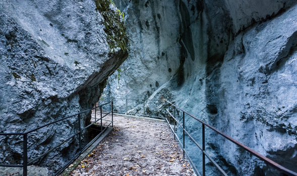 View of the narrow hiking trail through the Gola dell Infernaccio gorge with metal railings and towering limestone cliffs Montefortino Marche Italy. View of the narrow hiking trail through the Gola dell Infernaccio gorge with metal railings and towering limestone cliffs Montefortino Marche Italy.