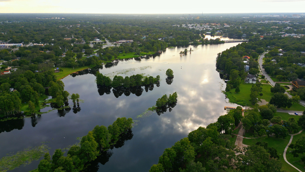 Aerial view of a serene lake surrounded by lush green trees and residential houses in a quiet neighborhood during golden hour in Tampa Florida United States. Aerial view of a serene lake surrounded by lush green trees and residential houses in a quiet neighborhood during golden hour in Tampa Florida United States.