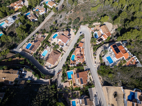Aerial view of residential villas with swimming pools and terracotta roofs nestled in the hills of Moraira Valencian Community Spain.