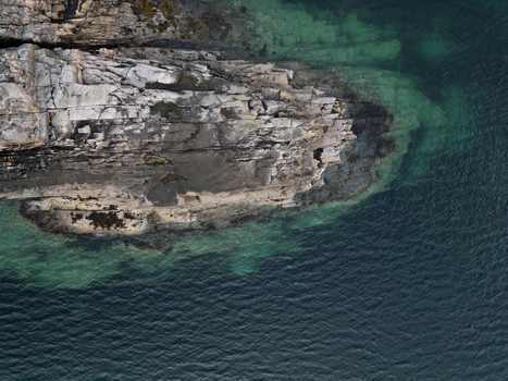 Aerial view of the rugged rocky coastline and clear turquoise water at Rorvikstranda Henningsvaer Nordland Norway.