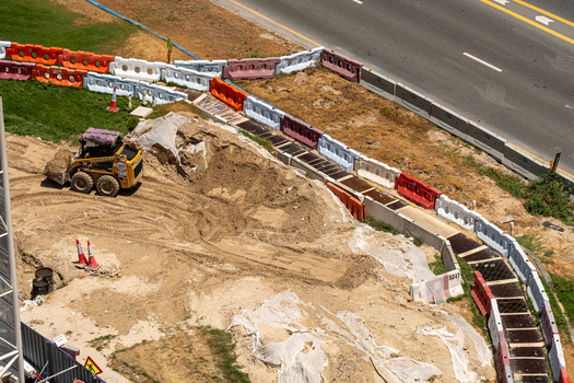 Aerial view of a yellow skid steer loader moving sand at a construction site bordered by colorful plastic barriers in Dubai Dubai United Arab Emirates. Aerial view of a yellow skid steer loader moving sand at a construction site bordered by colorful plastic barriers in Dubai Dubai United Arab Emirates.