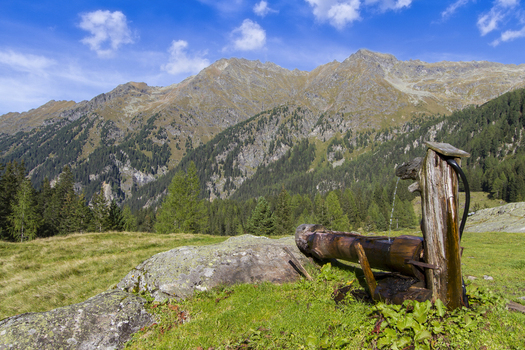 View of a rustic wooden water feature perched on a rocky outcrop against a backdrop of rugged mountains and lush greenery in Duisitzkarsee Austria. View of a rustic wooden water feature perched on a rocky outcrop against a backdrop of rugged mountains and lush greenery in Duisitzkarsee Austria.