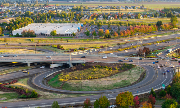 Aerial view of the Interstate 5 highway interchange with multi level ramps flowing traffic and suburban landscape with autumn foliage in Woodburn Oregon United States. Aerial view of the Interstate 5 highway interchange with multi level ramps flowing traffic and suburban landscape with autumn foliage in Woodburn Oregon United States.