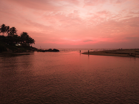 Aerial view of a tropical coastline with palm trees and people on the beach under a vibrant pink sunset sky in Galle Southern Province Sri Lanka. Aerial view of a tropical coastline with palm trees and people on the beach under a vibrant pink sunset sky in Galle Southern Province Sri Lanka.