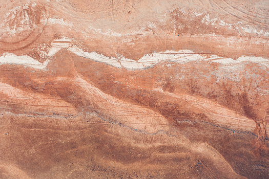 Aerial view of the reddish brown arid landscape with white mineral veins and tire tracks near Detwah Lagoon in Qalansiyah wa Abd Al Kuri Socotra Yemen. Aerial view of the reddish brown arid landscape with white mineral veins and tire tracks near Detwah Lagoon in Qalansiyah wa Abd Al Kuri Socotra Yemen.