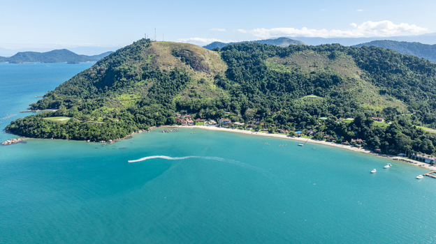 Aerial view of Ilha de Cataguas featuring lush green hills sandy beaches and turquoise waters with small boats in Angra dos Reis Rio de Janeiro Brazil.
