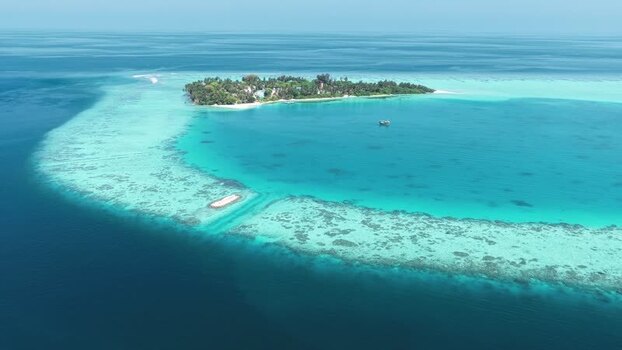 Aerial view of a tropical island and coral reef in the Maldives. Aerial view of a tropical island and coral reef in the Maldives.