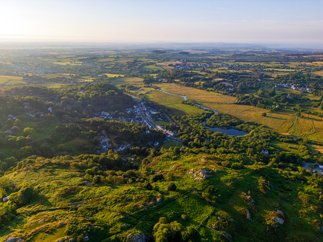 Aerial view of the village of Cwm y glo surrounded by lush green hills rocky terrain and a winding river under a soft golden hour light in Cwm y glo Wales United Kingdom. Aerial view of the village of Cwm y glo surrounded by lush green hills rocky terrain and a winding river under a soft golden hour light in Cwm y glo Wales United Kingdom.