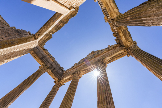 View of the ancient Roman columns of the Capitolium at Dougga Archaeological Site under a bright sun and clear blue sky in Teboursouk Beja Governorate Tunisia.