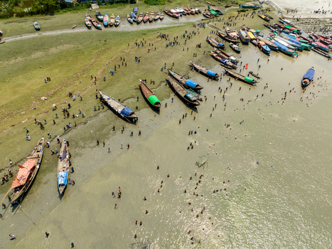 Aerial view of a bustling riverbank teeming with boats and people the muddy shores reflecting the sunlight creating a vibrant chaotic scene Charmonai Barisal Division Bangladesh. Aerial view of a bustling riverbank teeming with boats and people the muddy shores reflecting the sunlight creating a vibrant chaotic scene Charmonai Barisal Division Bangladesh.