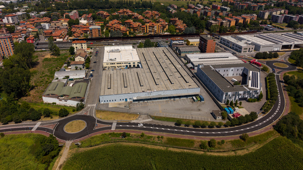 Aerial view of a large industrial warehouse complex surrounded by residential buildings green trees and a roundabout in Milan Lombardy Italy. Aerial view of a large industrial warehouse complex surrounded by residential buildings green trees and a roundabout in Milan Lombardy Italy.