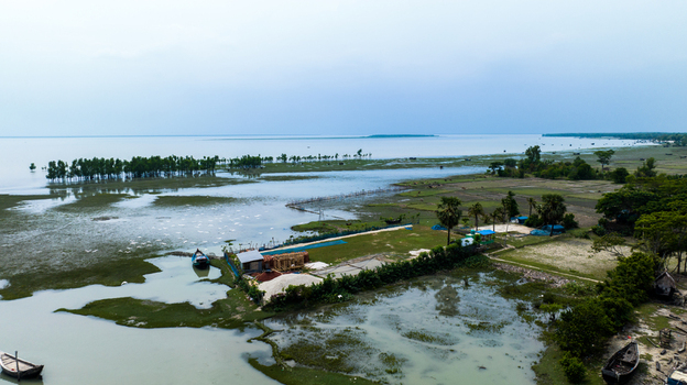 Aerial view of the coastal wetlands small wooden boats and lush vegetation along the river channels in Patharghata Barisal Division Bangladesh. Aerial view of the coastal wetlands small wooden boats and lush vegetation along the river channels in Patharghata Barisal Division Bangladesh.
